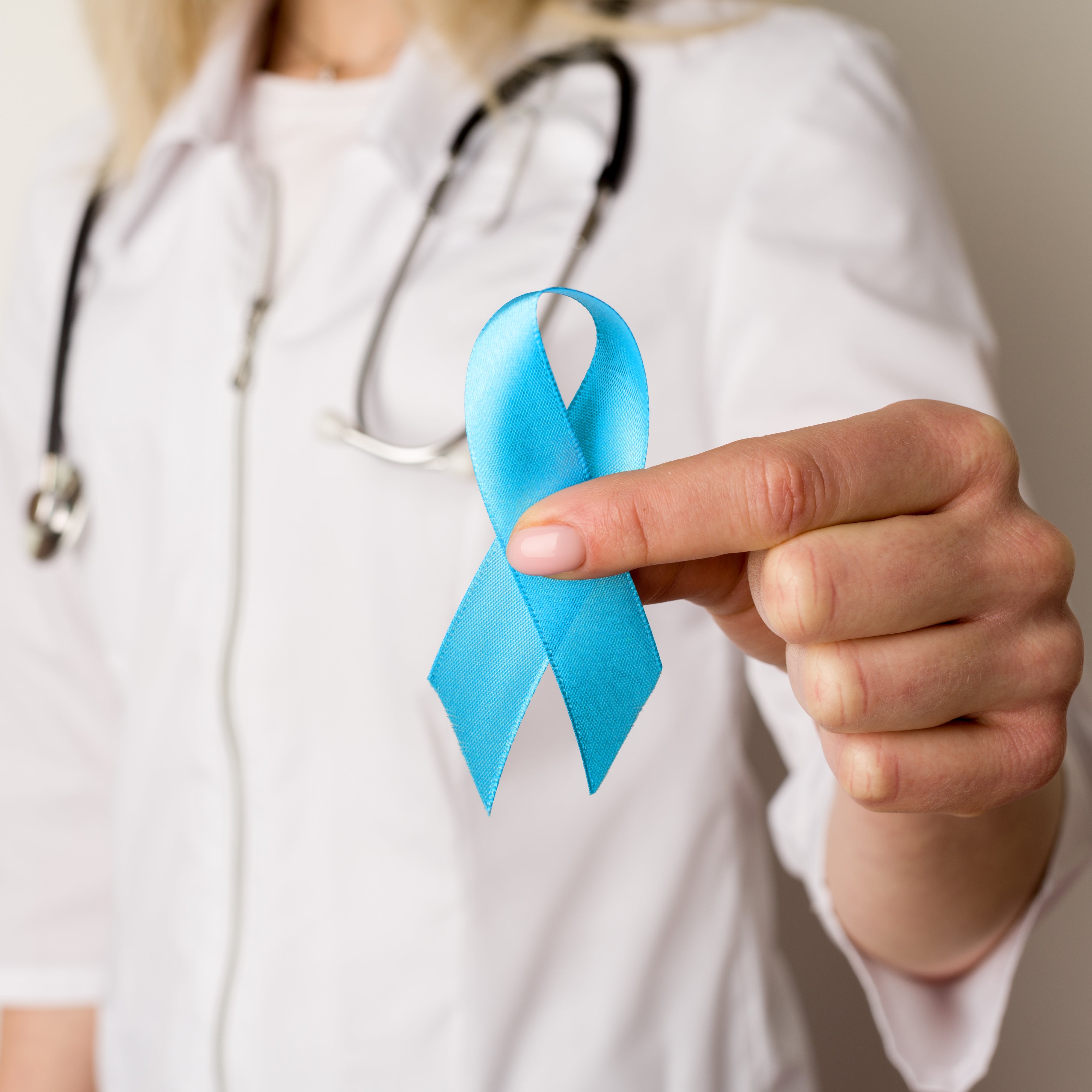 Healthcare professional holds blue ribbon symbolizing prostate cancer awareness, promoting prostate health and men's vitality.