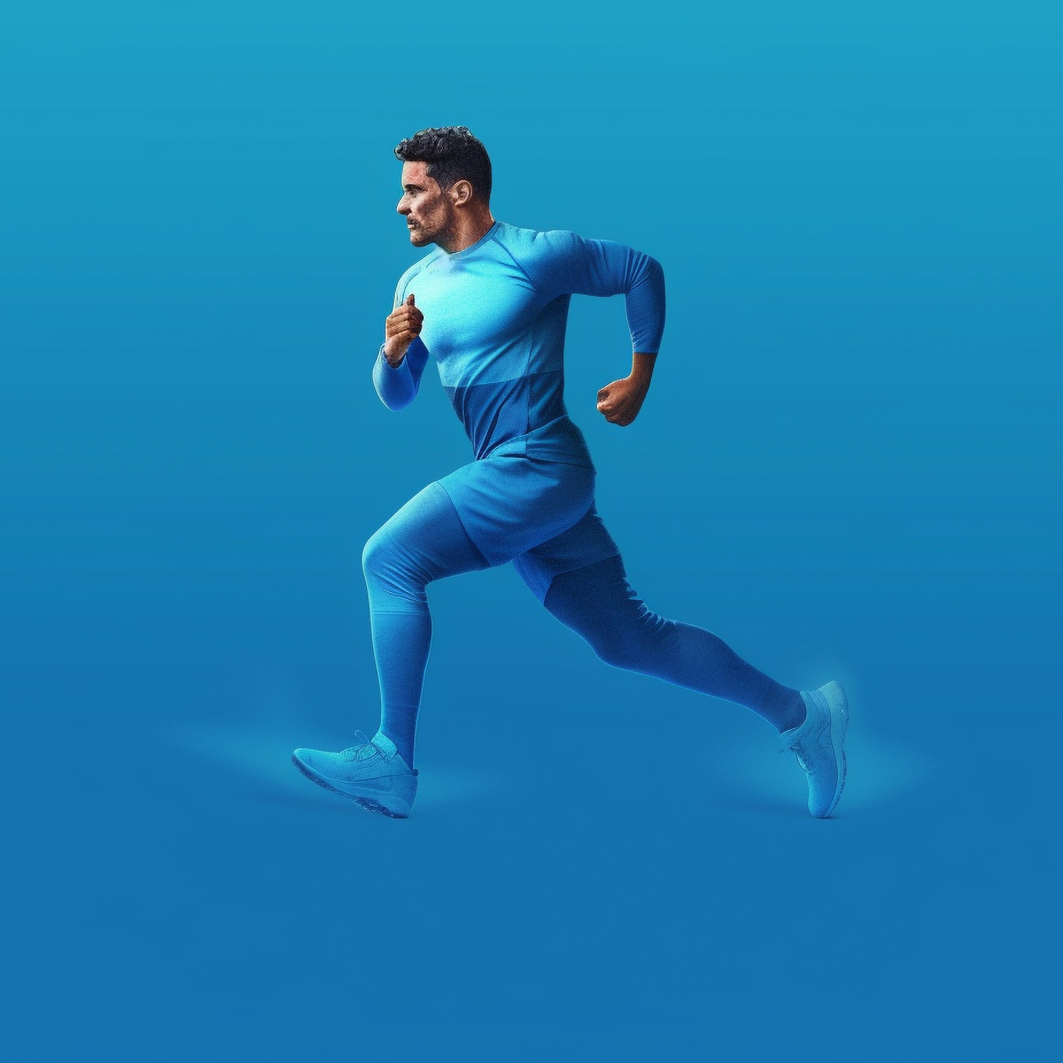Man running in a blue athletic outfit, exuding energy & stamina with a determined expression for an active, dynamic lifestyle.