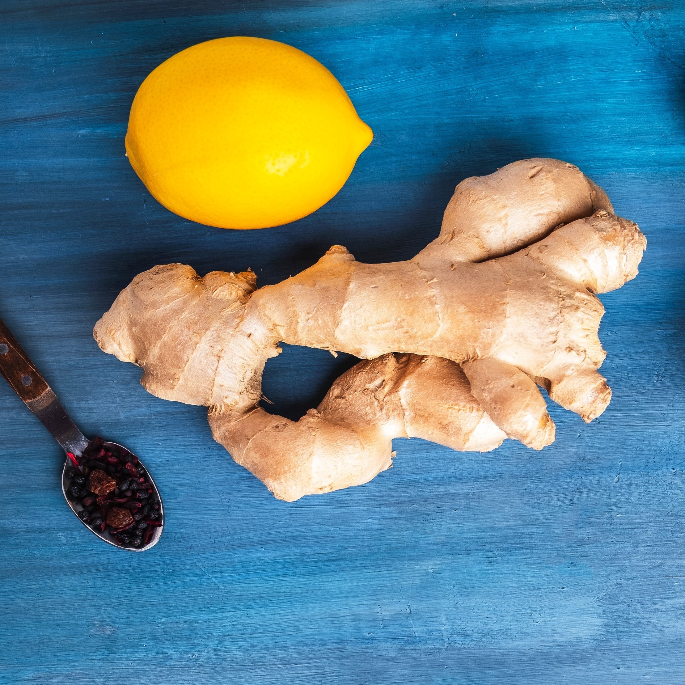 Top-down view of lemon, ginger, and berries on a blue surface promotes healing with natural anti-inflammatories, enhancing overall well-being and active life.